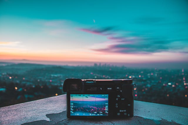 A digital camera is set up on top of a roof to take photos of the city at night.