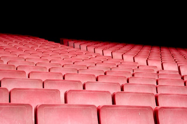 A photo of empty, red seats in a theater.