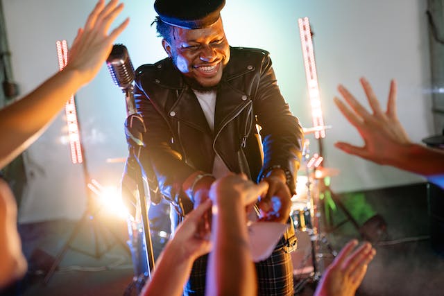 A man stands on a stage and signs autographs for his fans.