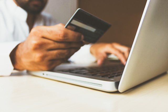 A person using a laptop and a credit card to make an online payment.