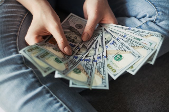 A person holding dollar notes in their hands.