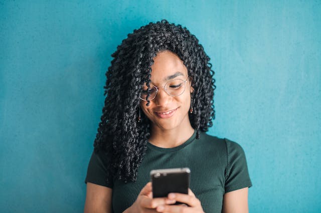 A woman smiles as she watches TikTok Stories on her phone.
