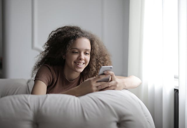 A woman on a couch watches TikTok videos on her phone.