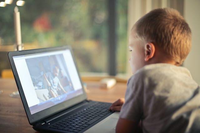 A boy watches a video on a laptop.