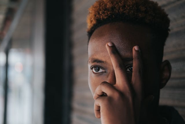 A person holds a hand over their face and peeks between two fingers.