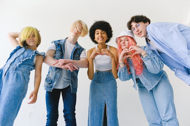 A group of young people pose in front of the camera while making heart signs with their hands.