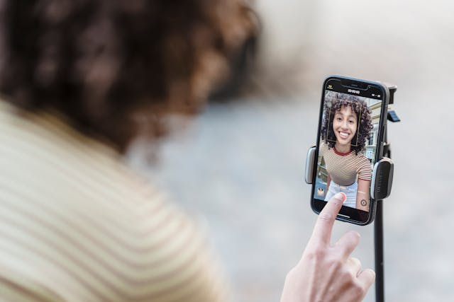 A woman presses the record button on her phone to start her TikTok video.