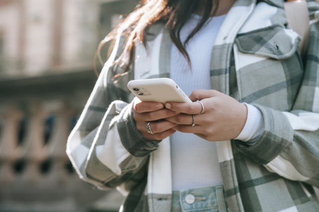 A woman uses both hands to type on her phone.