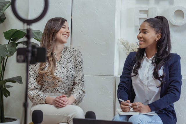 Two women sit down to record an interview.