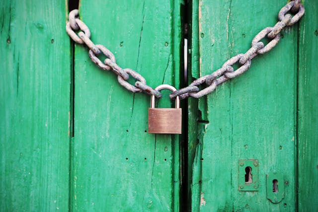 Green wooden doors are locked with a chain and padlock.