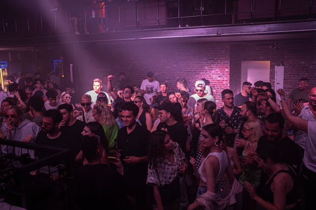 A lively audience gathers inside a dim club.