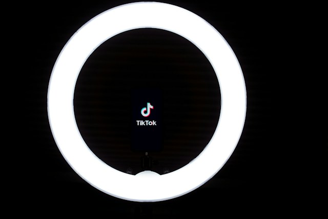 A phone inside a round ring light displays the TikTok logo.