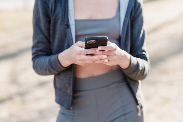 A woman in a running outfit uses her phone to browse on TikTok.