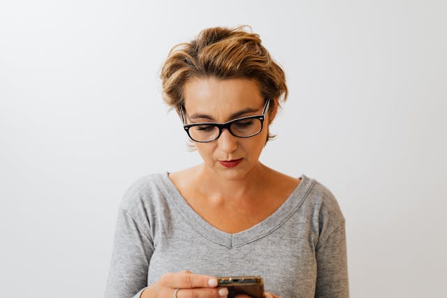 A woman checks her phone for TikTok notifications.