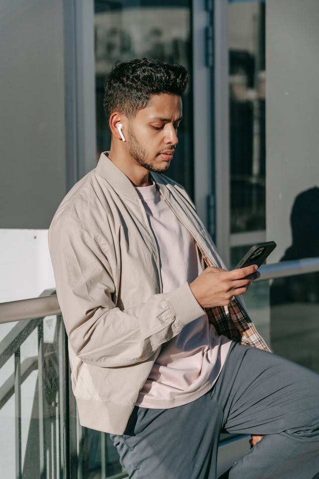 A man with Airpods scrolls through his phone.