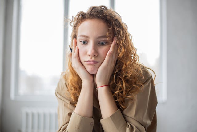 A woman looks bewildered and puts her face between her hands.