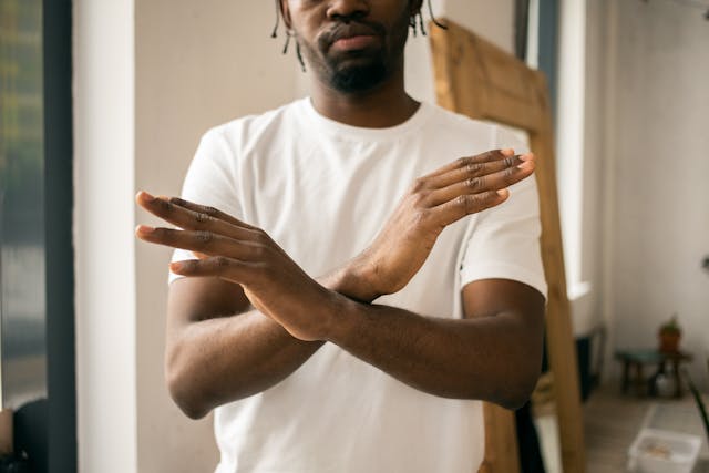 A man demonstrates the stop gesture with his arms crossed at the wrists.
