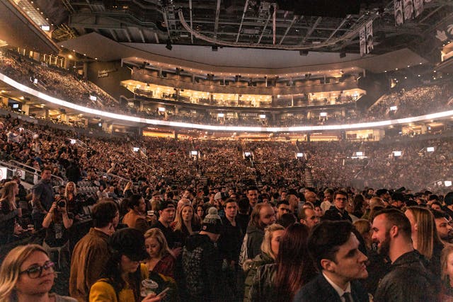 Tens of thousands of people gather in a giant stadium for a live event.