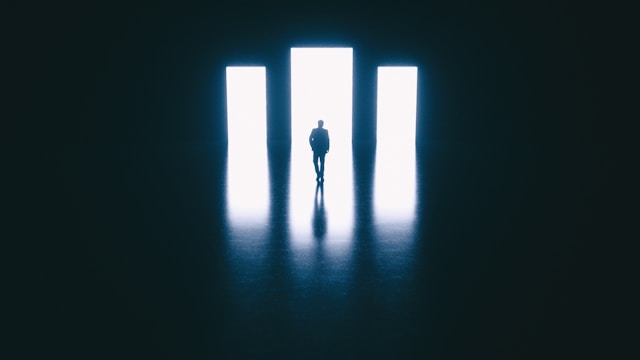 A person’s silhouette in front of three arched doorways.