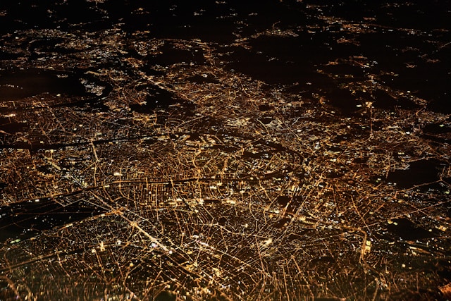An aerial view of a city shows places lighted up at night.