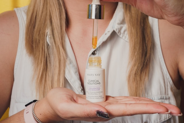 A woman holds a bottle of beauty serum in her hand for a sponsored video.