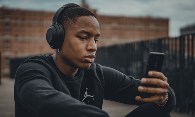 A person with headphones watches TikTok videos on his phone.