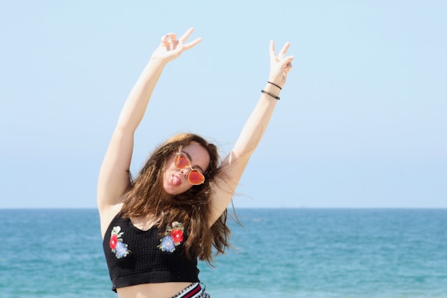 A woman raises her arms above her head, makes two peace signs, and sticks her tongue out for her TikTok profile pic.