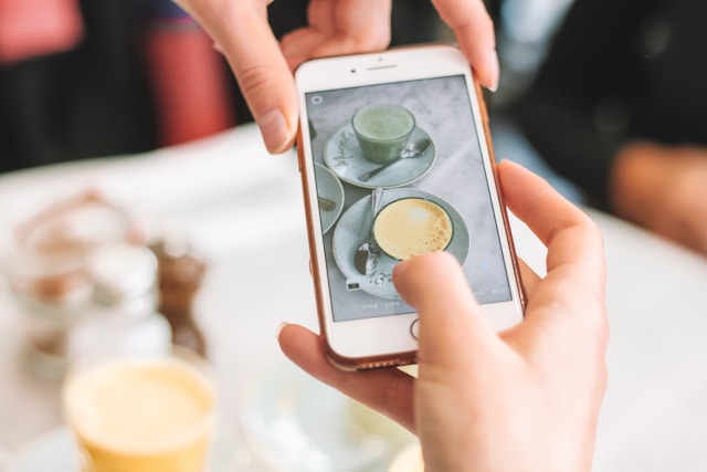 A person uses their phone to take a photo of their drinks for a TikTok photo post.