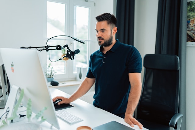A creator stands in front of a microphone and computer and creates content for a sponsored post.