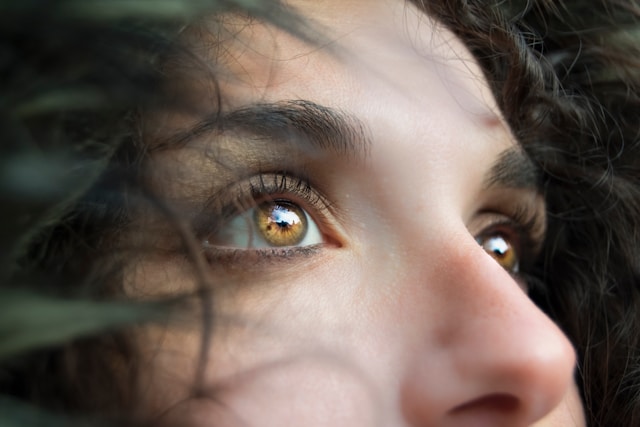 A close-up, angled shot of a woman’s amber eyes.