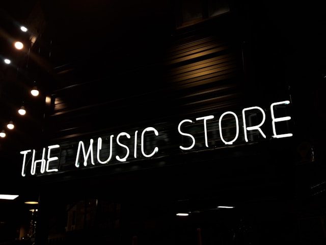 A big white neon sign that reads “The Music Store” is on a wall.