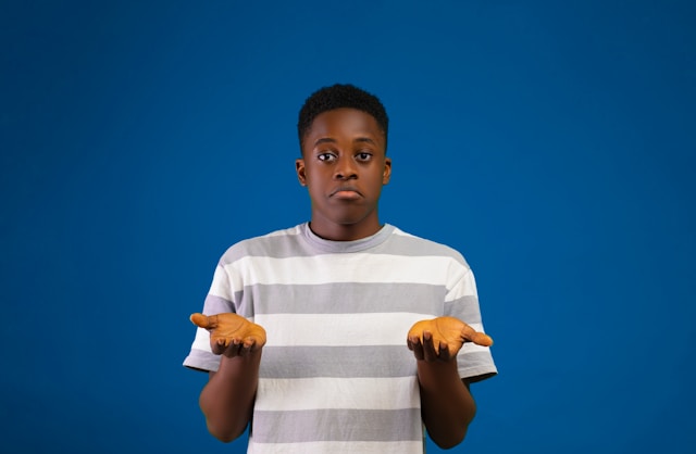 A boy holds his palms out to express confusion.