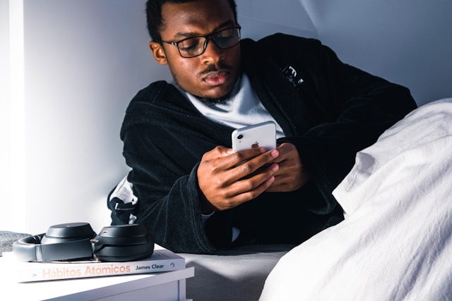 A man browses on his phone while in bed.