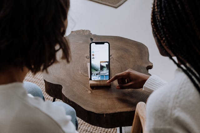 Two people sit side-by-side and watch videos on a smartphone.