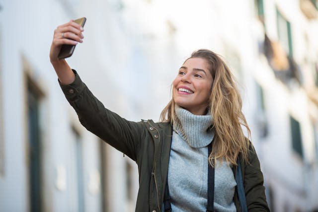 A woman takes a selfie with her cell phone.