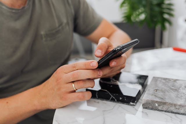 A person sits at a desk with their cell phone.