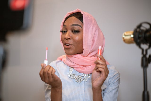 A woman in a hijab records a makeup video.