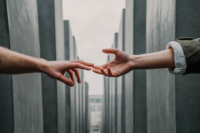 Two arms stretch out and touch each other’s fingers.