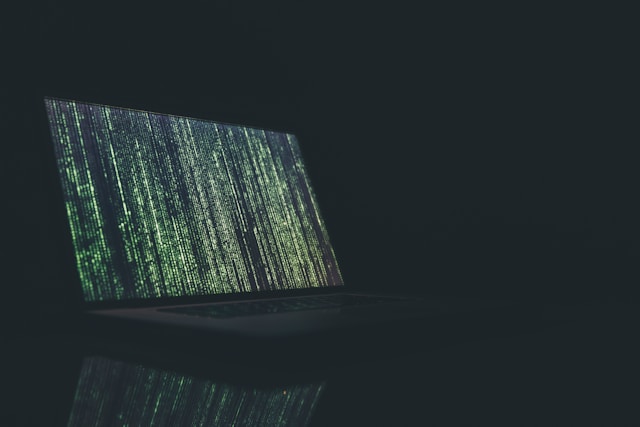 Rows of computer code fill a laptop screen.