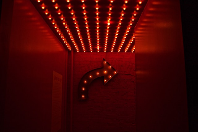 An arrow-shaped sign with red light bulbs.