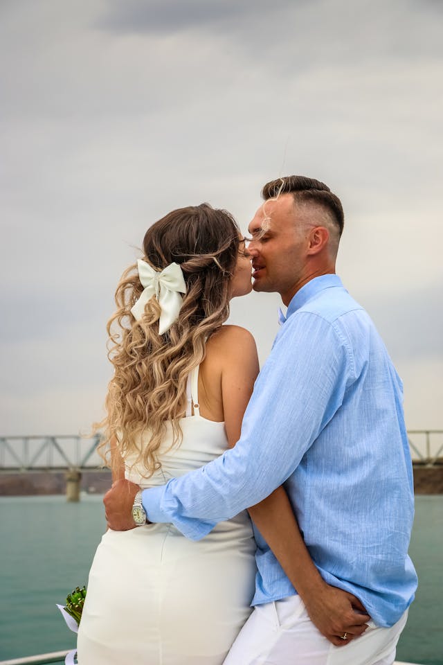 A woman with a hair bow kisses a man.