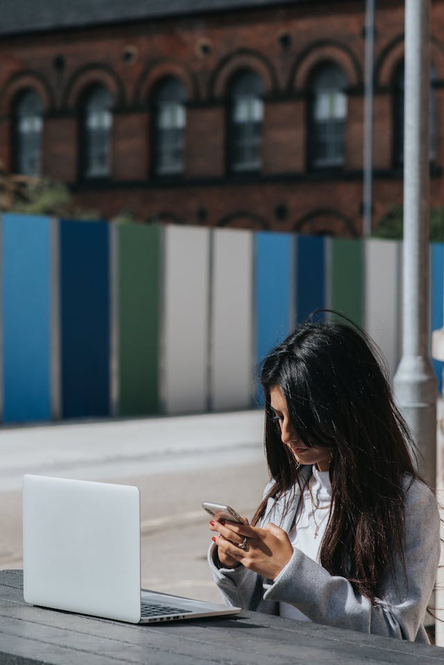 A woman looks down at her cell phone with a serious expression.