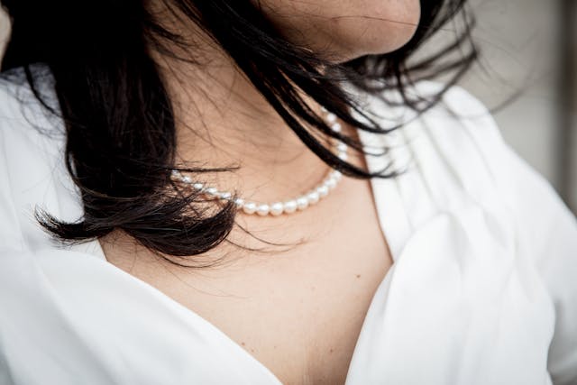 A string of pearls hangs from a woman’s neck.