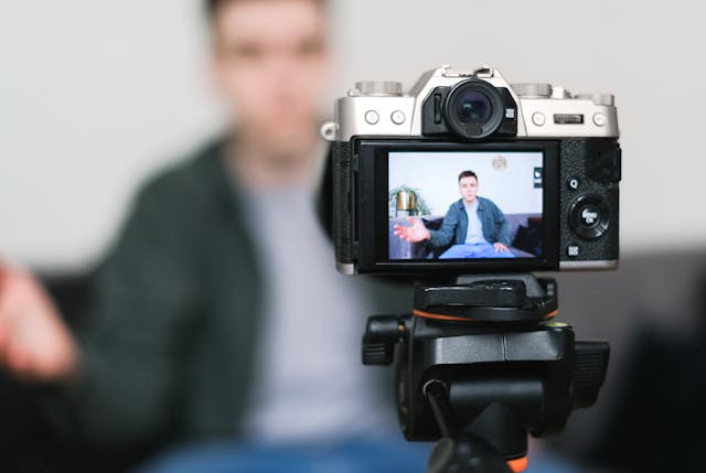 A digital camera screen shows a man speaking.