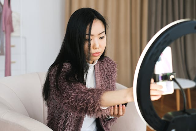 A woman adjusts her phone while recording herself.