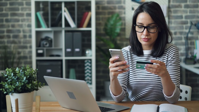 A woman enters her credit card information into her phone.