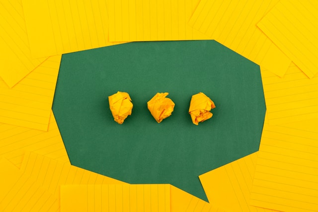 Three pieces of crumpled yellow paper inside a green chat bubble.