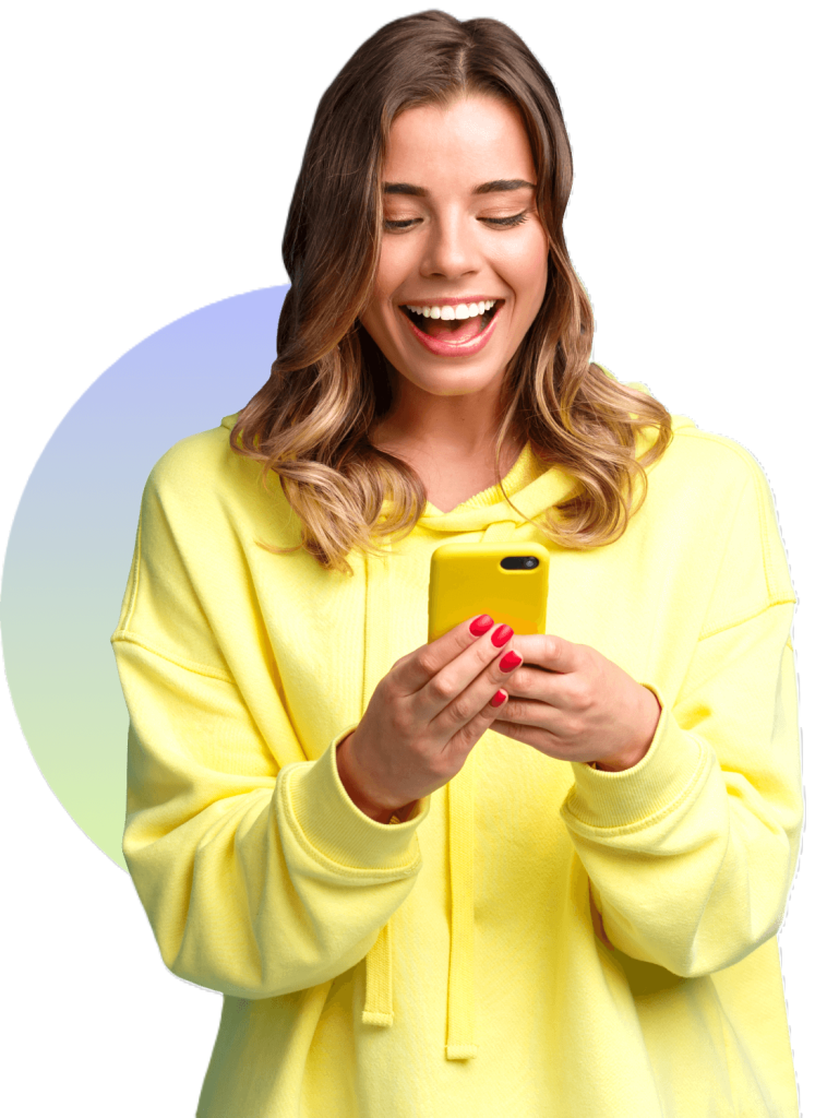 A woman wears a big smile as she looks at her phone.