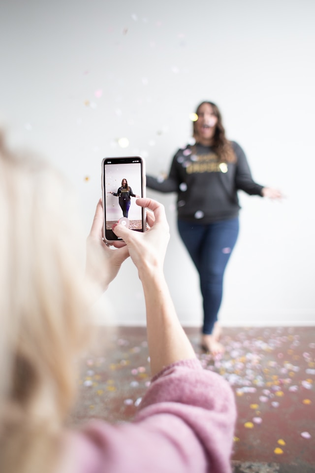 A woman records another woman using her phone for a TikTok video.