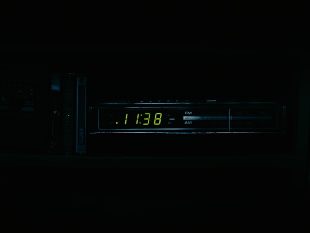 A digital clock glows green in the dark.